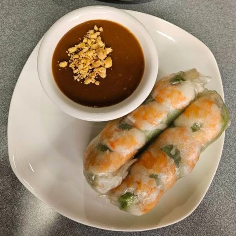 Two fresh Vietnamese spring rolls with shrimp and greens, served with a peanut dipping sauce.