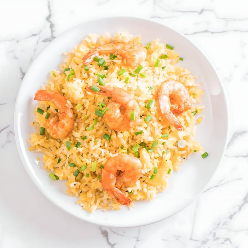 Shrimp fried rice with chopped green onions on a white plate, from Pho Thien Phat.